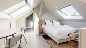 Une chambre avec un puits de lumière, un lit, un bureau et une chaise.