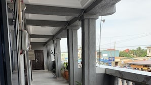 A covered balcony with tiled flooring, columns, and potted plants. - Central Reservations Apartment (Accra)