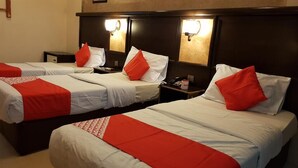 A hotel room with two beds, each with a red and white bedspread and matching pillows. There are bedside tables with lamps and a telephone. - RAHAB HOTEL (Dubai)
