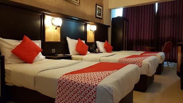 A hotel room with three beds, each with white bedding and red accents, and a red patterned throw. - RAHAB HOTEL (Dubai)