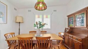 A dining room with a wooden table and chairs, a vase with flowers, and a stained glass cabinet.