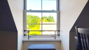 Une petite pièce fermée, avec une fenêtre, un banc et une chaise.
