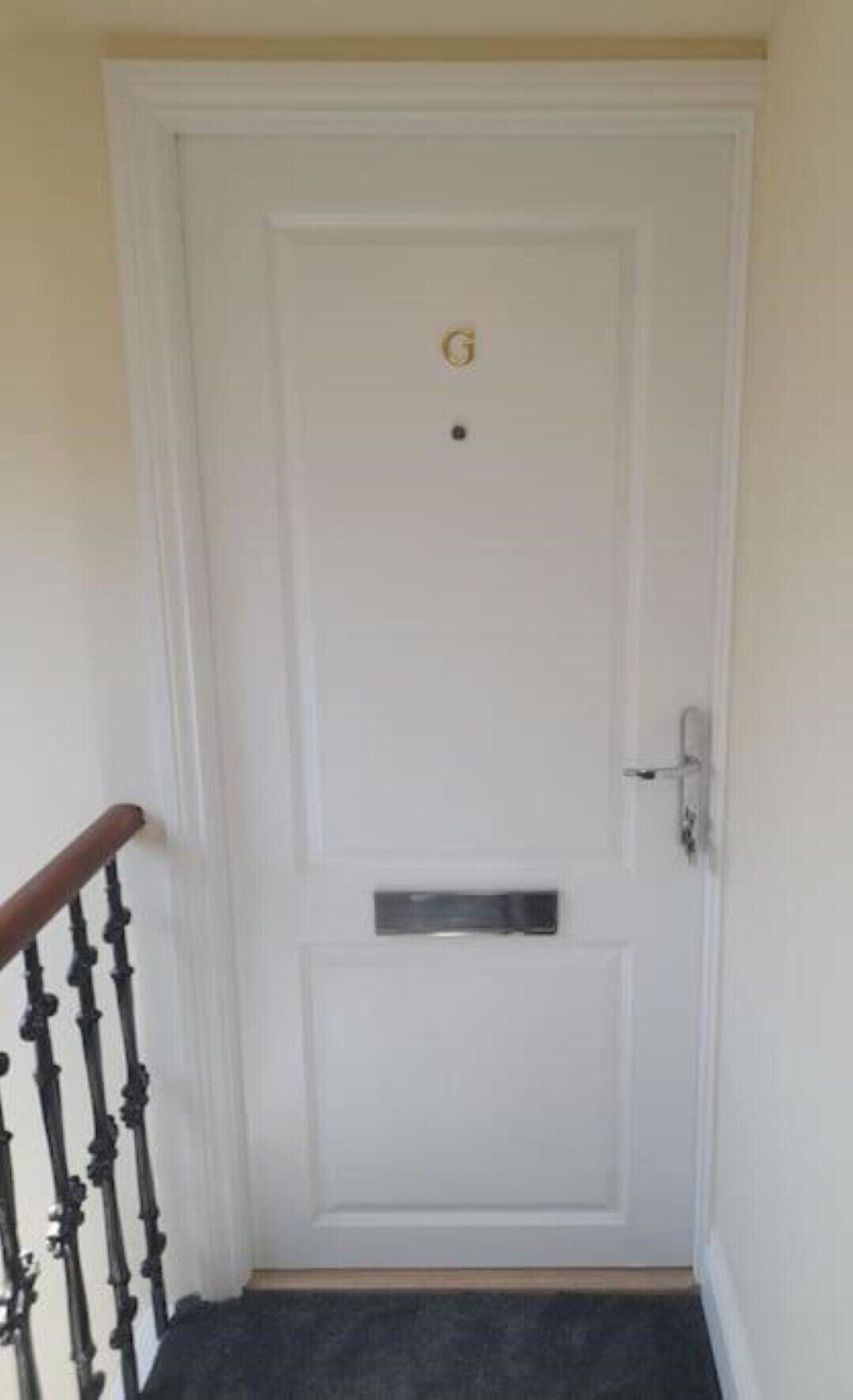 A white door with a small rectangular mail slot and a doorbell.