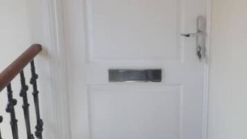 A white door with a small rectangular mail slot and a doorbell.