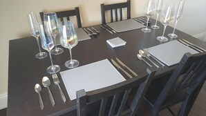 Une table à manger dressée pour six personnes, avec des verres à vin, des couverts et une décoration de table.