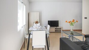 A modern living room with a dining area, a sofa, and a TV. - Apartamento de Vacaciones (Alacant)