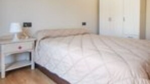 A bedroom with a bed, a nightstand, and a wardrobe. - Apartamento de Vacaciones (Alacant)