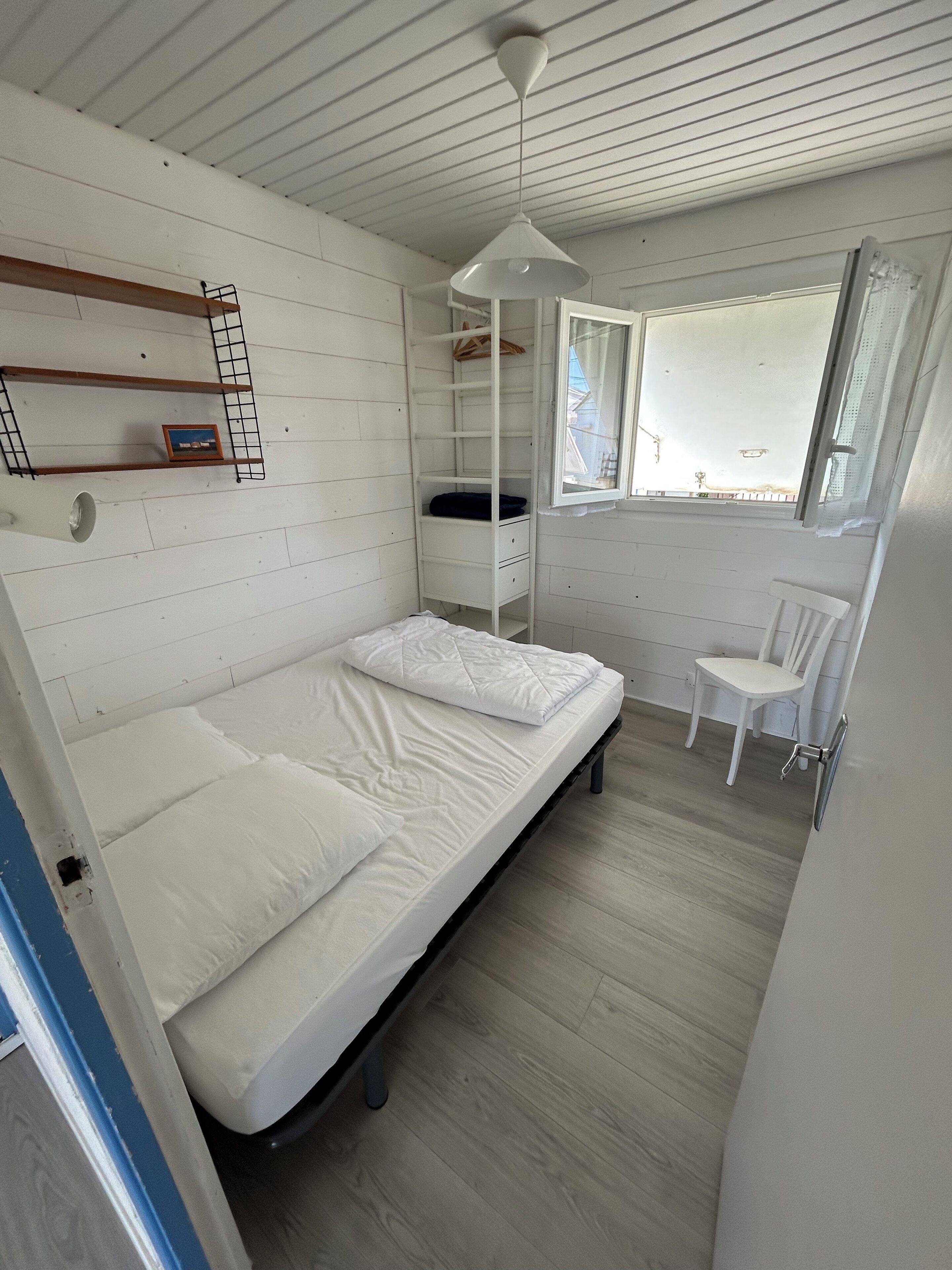 Une petite pièce comprenant un lit superposé, un bureau et une chaise.