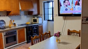 A kitchen with wooden cabinets, a microwave, an oven, and a dining table with chairs.