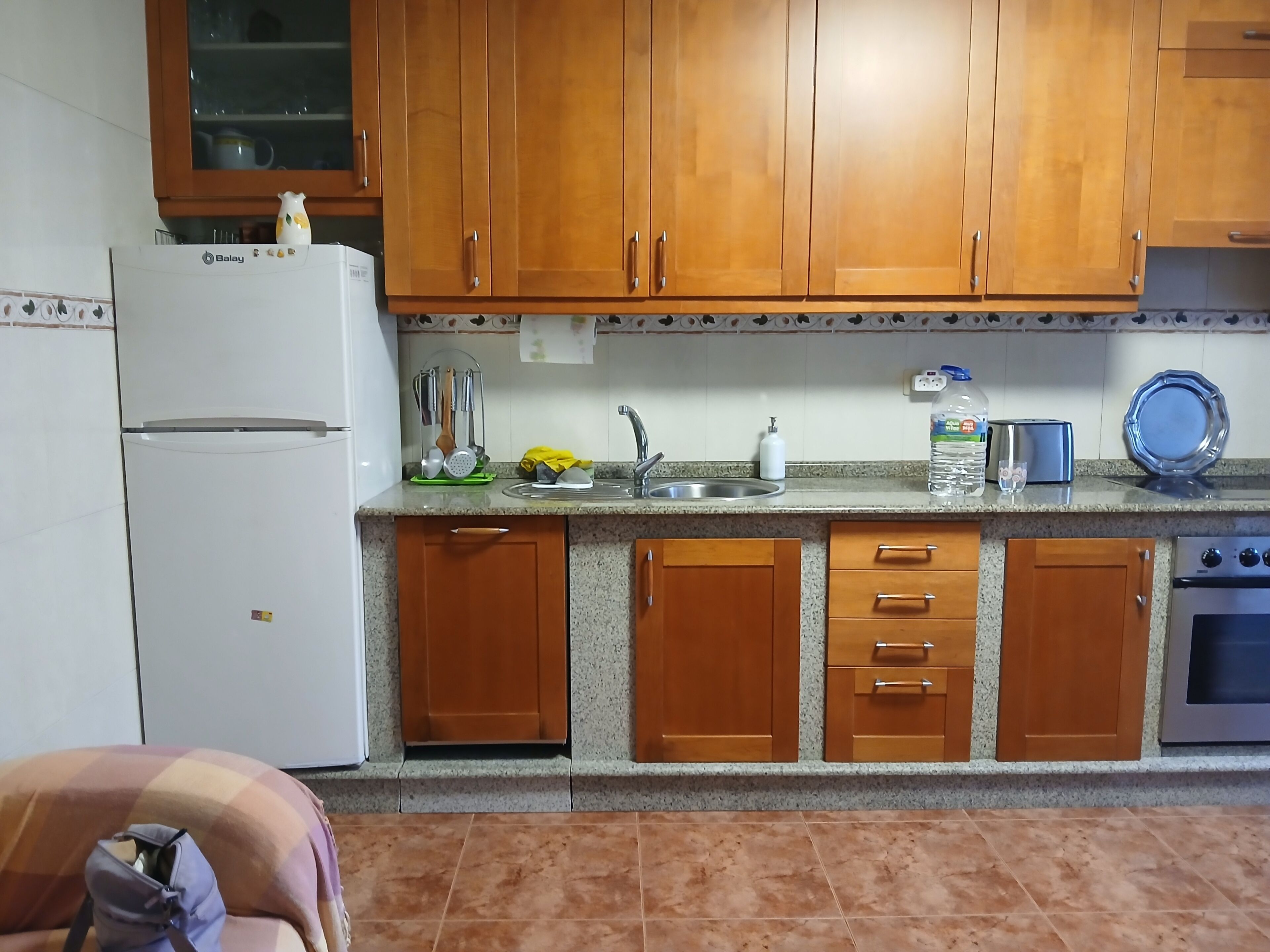 Una cocina con armarios de madera, un refrigerador blanco, un fregadero y un tostador.