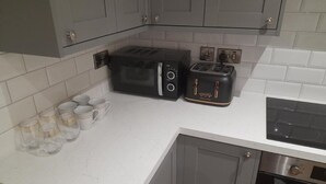 Una cocina con armarios grises, un microondas negro, un tostador negro y un horno de acero inoxidable.