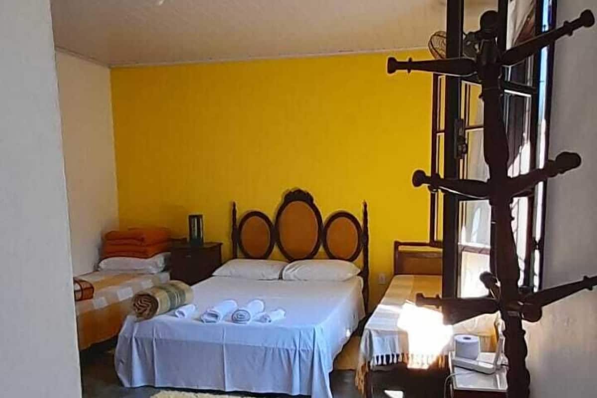 Ein Zimmer mit zwei Betten, einer Holzleiter, einem Nachttisch und einem Fenster.