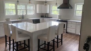Een moderne keuken met een centraal eiland, witte kasten en hanglampen.