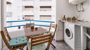 A balcony with a wooden table and chairs, a washing machine, and a water heater. - Apartment Ricardo - 200m to the beach (Armação de Pêra)