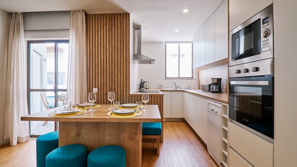 A modern kitchen with wooden cabinetry, a built-in microwave, and a dishwasher. - Apartment Ricardo - 200m to the beach (Armação de Pêra)