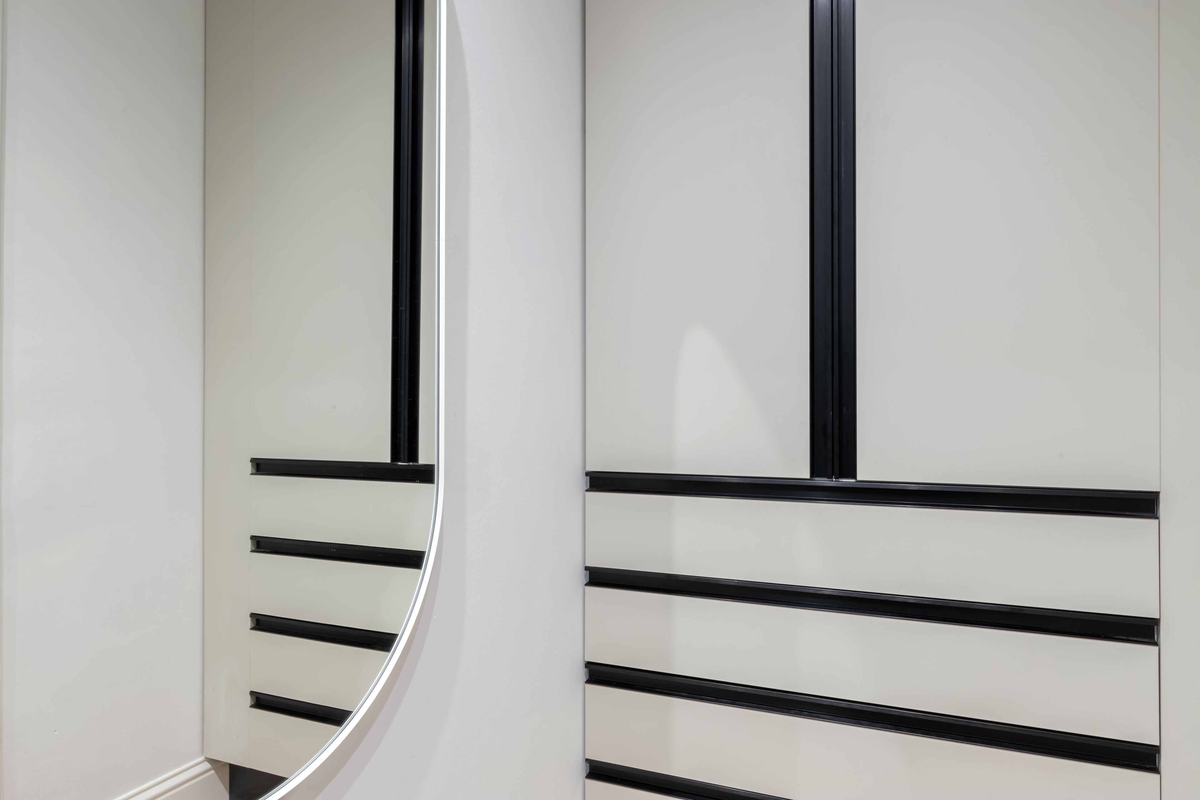 A modern interior with a curved white wall and black horizontal lines.