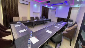 Une salle de conférence équipée d’une longue table, de chaises, d’un écran de projection et d’un distributeur d’eau.