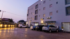 Un hôtel à plusieurs étages avec plusieurs voitures garées sur le parking.
