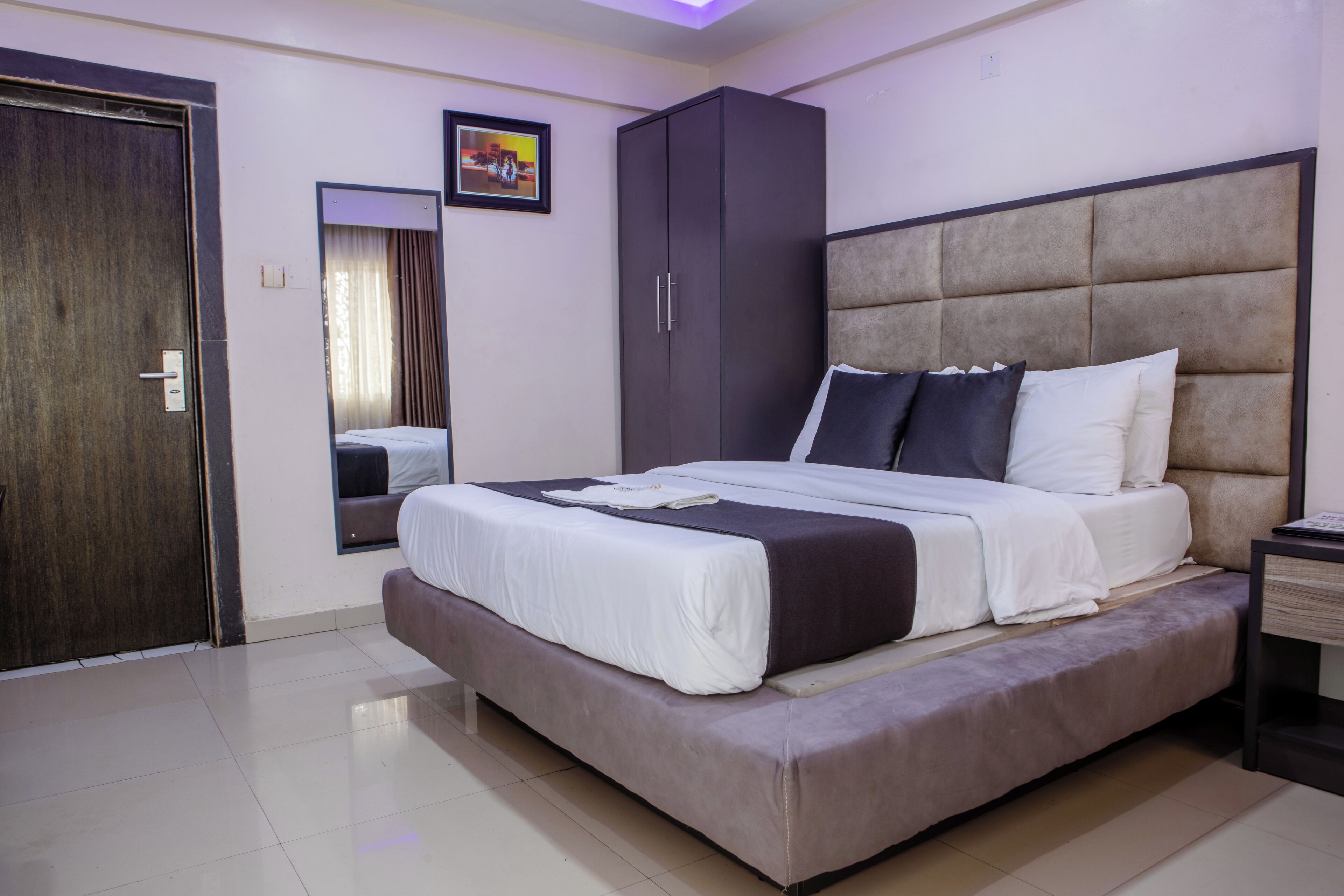 A bedroom with a bed, a wardrobe, a mirror, and a door.