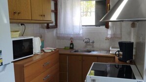 Una cucina compatta con mobili in legno, un frigorifero bianco, un forno a microonde, un lavello e un piano cottura.