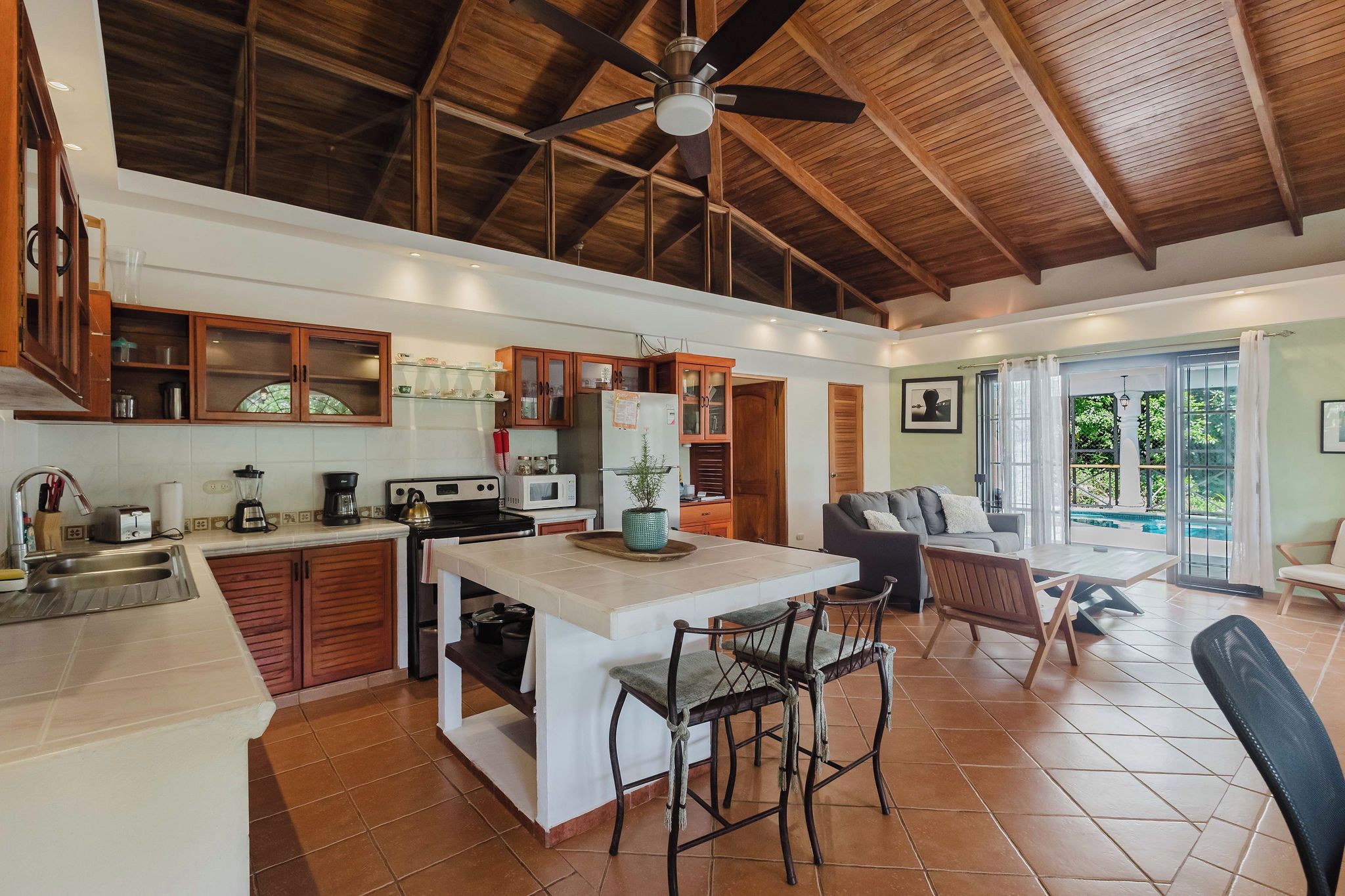 Una cocina amplia con una isla central, armarios de madera y un ventilador de techo.