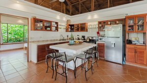 Un'ampia cucina con isola centrale, mobili in legno e una ventola a soffitto.