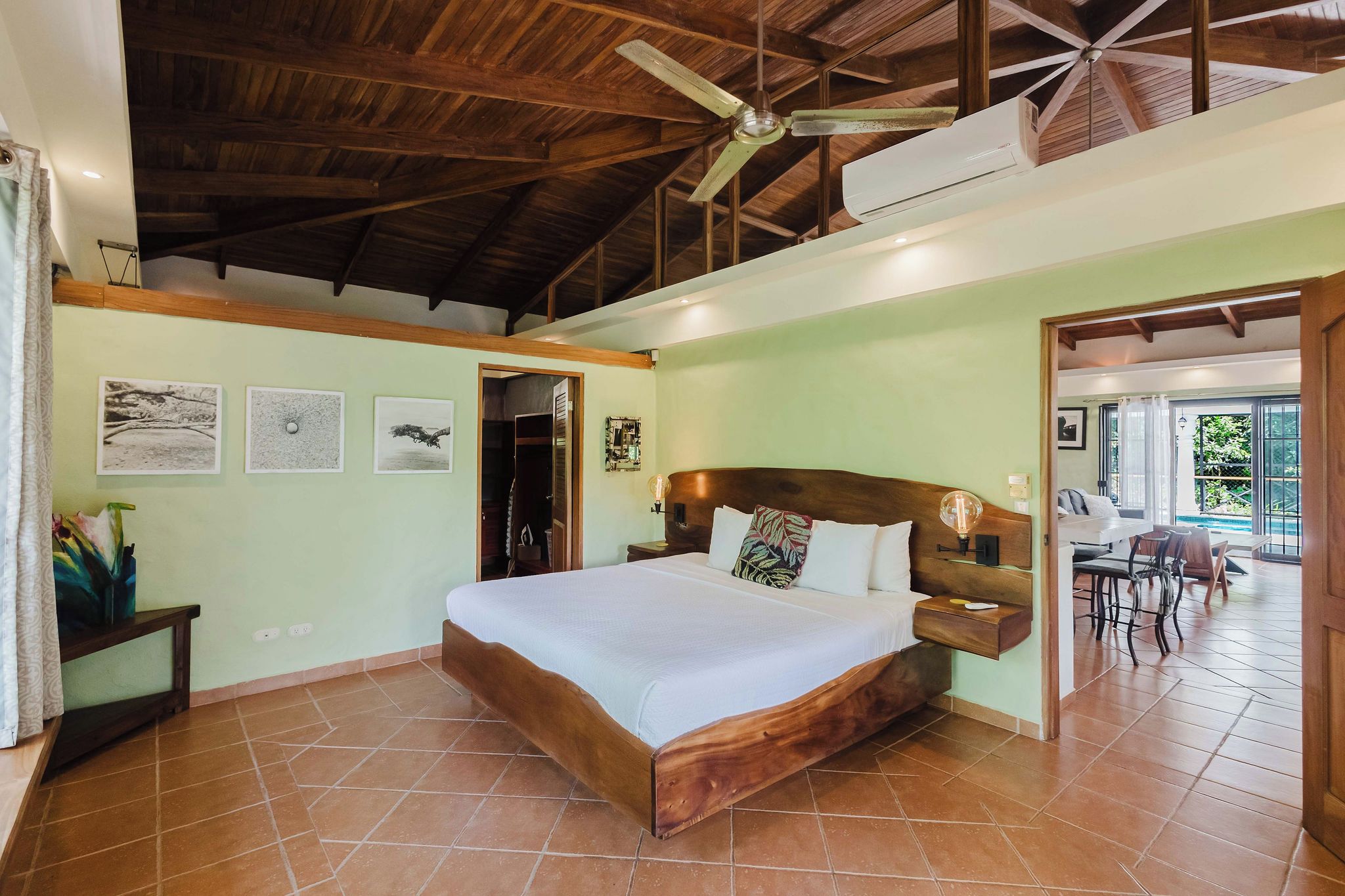 Une chambre avec un lit en bois, un ventilateur de plafond et une vue sur un patio.