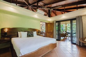 A bedroom with a large bed, wooden headboard, and a nightstand with a lamp. - A spacious, 2 bed Penthouse with private pool & parking in Manuel Antonio. (Quepos)