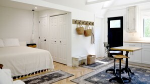 A bedroom with a large bed, a desk with a chair, and a wardrobe.