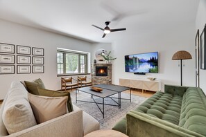 Een moderne woonkamer met een open haard, een televisie en een groene bank.