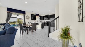A modern apartment with a living room, dining area, kitchen, and a staircase. - Luxury 6 Bedroom 5 Bathroom Gated Resort Villa Close to Disney (Davenport)