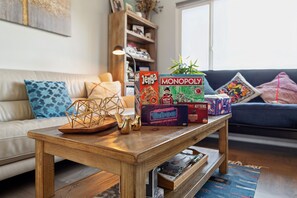 A living room with a wooden coffee table displaying board games like Monopoly and Jenga.