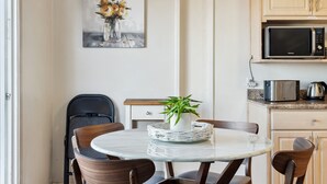 A dining area with a round table, four chairs, a potted plant, and a microwave in the background. - SF Home with SPECTACULAR VIEW- Minutes to downtown (San Francisco)