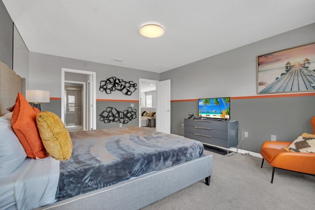 A modern bedroom with a large bed, a TV, and a dresser.