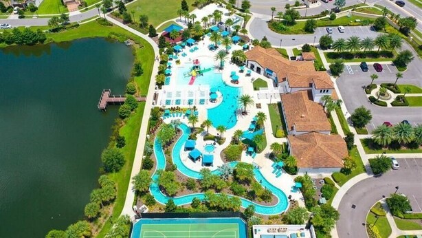 An aerial view of a resort with a large swimming pool, a tennis court, and a dock by a lake. - 5 Bedroom  Home 8 Minutes To Disney and Parks (Kissimmee)
