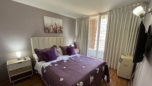 Ein Schlafzimmer mit Bett, Nachttisch, Lampe und einem Bild an der Wand.