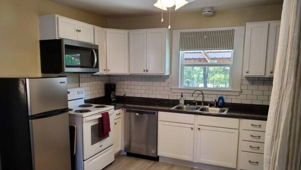 A kitchen with white cabinets, a microwave, a stove, a dishwasher, and a window with blinds. - Pet friendly!  Close to Temple hospitals. (Temple)