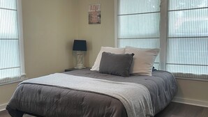 A bedroom with a bed, a ceiling fan, a nightstand, a lamp, and a window with blinds. - Pet friendly!  Close to Temple hospitals. (Temple)