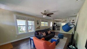 A spacious living room with a dark brown sofa, a bright orange armchair, and a ceiling fan. - Pet friendly!  Close to Temple hospitals. (Temple)