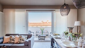 Ein modernes Wohnzimmer mit einer Couch, einem Esstisch und Stühlen. Ein großes Fenster bietet Blick auf die Stadt.