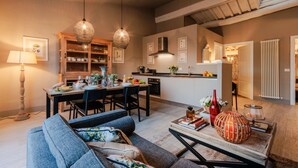 Eine moderne Küche mit Holzschränken, ein Essbereich mit Tisch für vier Personen und ein gemütliches Wohnzimmer mit Sofa und Couchtisch.