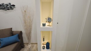 Ein Zimmer mit einem braunen Sofa, einer dekorativen Vase und einem an der Wand befestigten Regal mit verschiedenen Gegenständen.