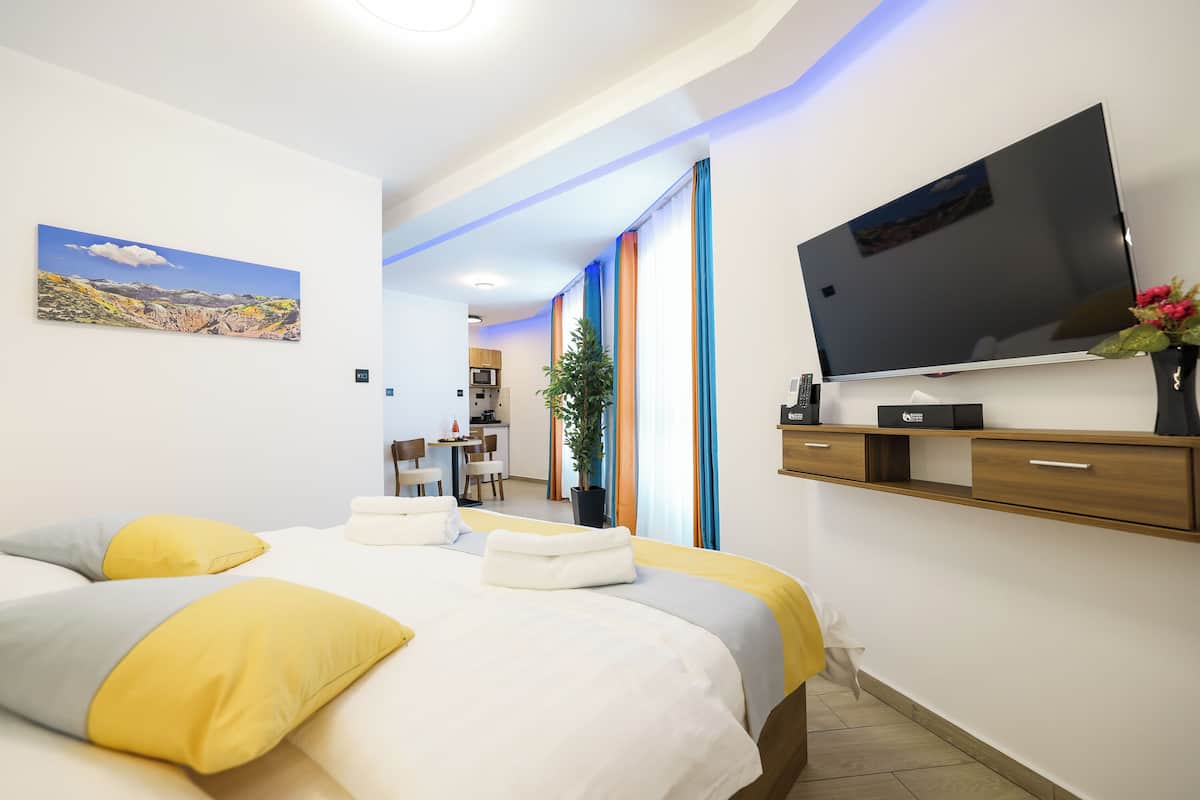 Une chambre d’hôtel moderne dotée d’un grand lit, d’un téléviseur à écran plat, d’un bureau et d’une plante en pot.