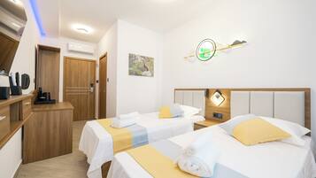A hotel room with two beds, a wooden desk, and a wall-mounted light fixture.