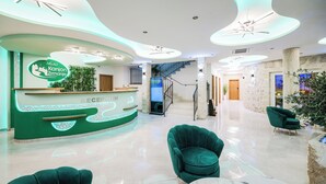A hotel reception area with a modern design, including a reception desk, green chairs, and a staircase in the background. - Hotel Kanjon Zrmanje (Obrovac)