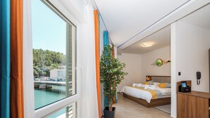 A modern hotel room with a large window, a bed, a desk, and a potted plant. - Hotel Kanjon Zrmanje (Obrovac)