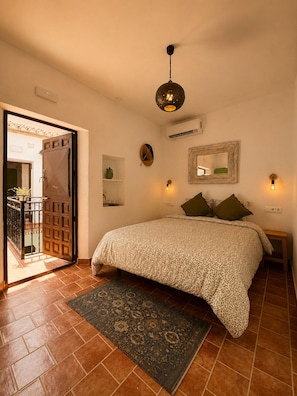 Un dormitorio con cama, alfombra, una puerta y una lámpara fijada a la pared.