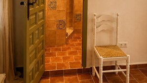 Une pièce avec une porte verte, une chaise blanche et un sol carrelé.