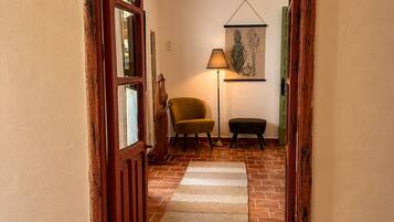 Un pasillo con puerta de madera, una lámpara, una silla y una alfombra.