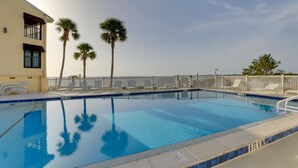 A rectangular pool with clear blue water, surrounded by a white fence and palm trees. - Beach Retreat w/ Pool & Fishing Dock (Port Charlotte)